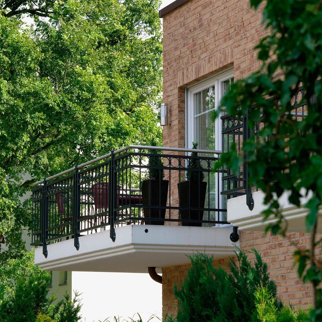 A balcony with wrought iron lattice on a brick house.