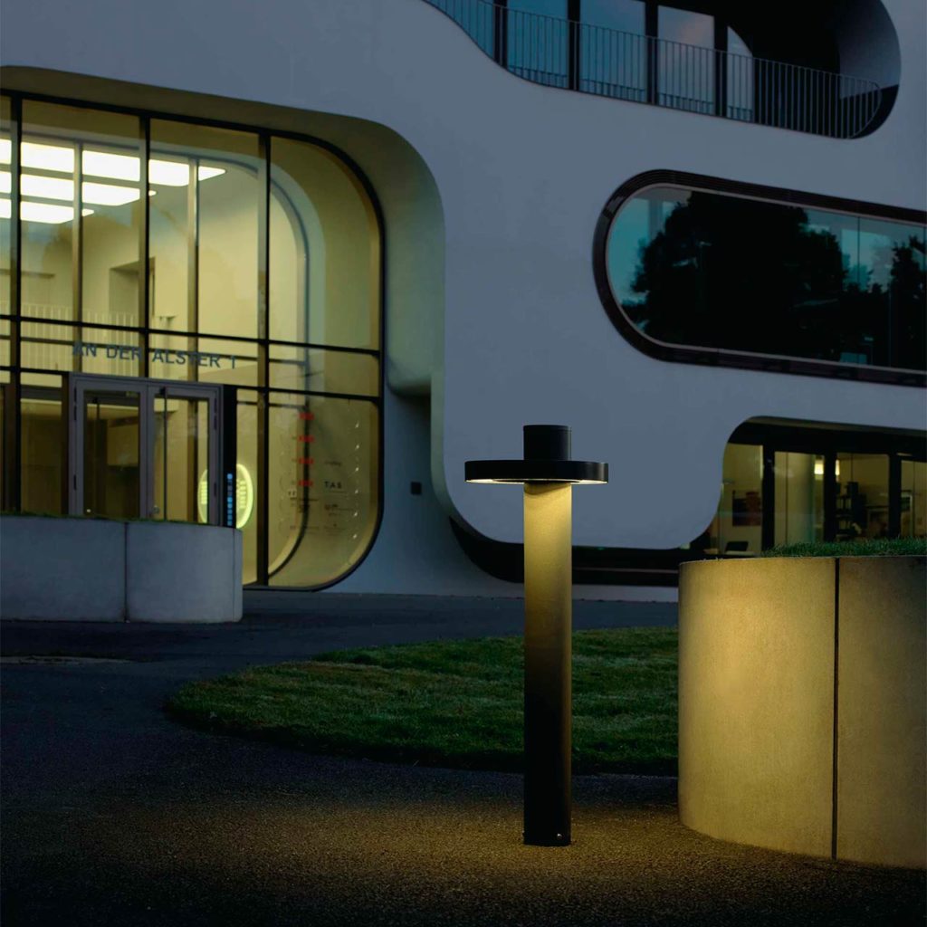 Eine stilvolle Objektlbeleuchtung steht neben einem großen Bürogebäude.