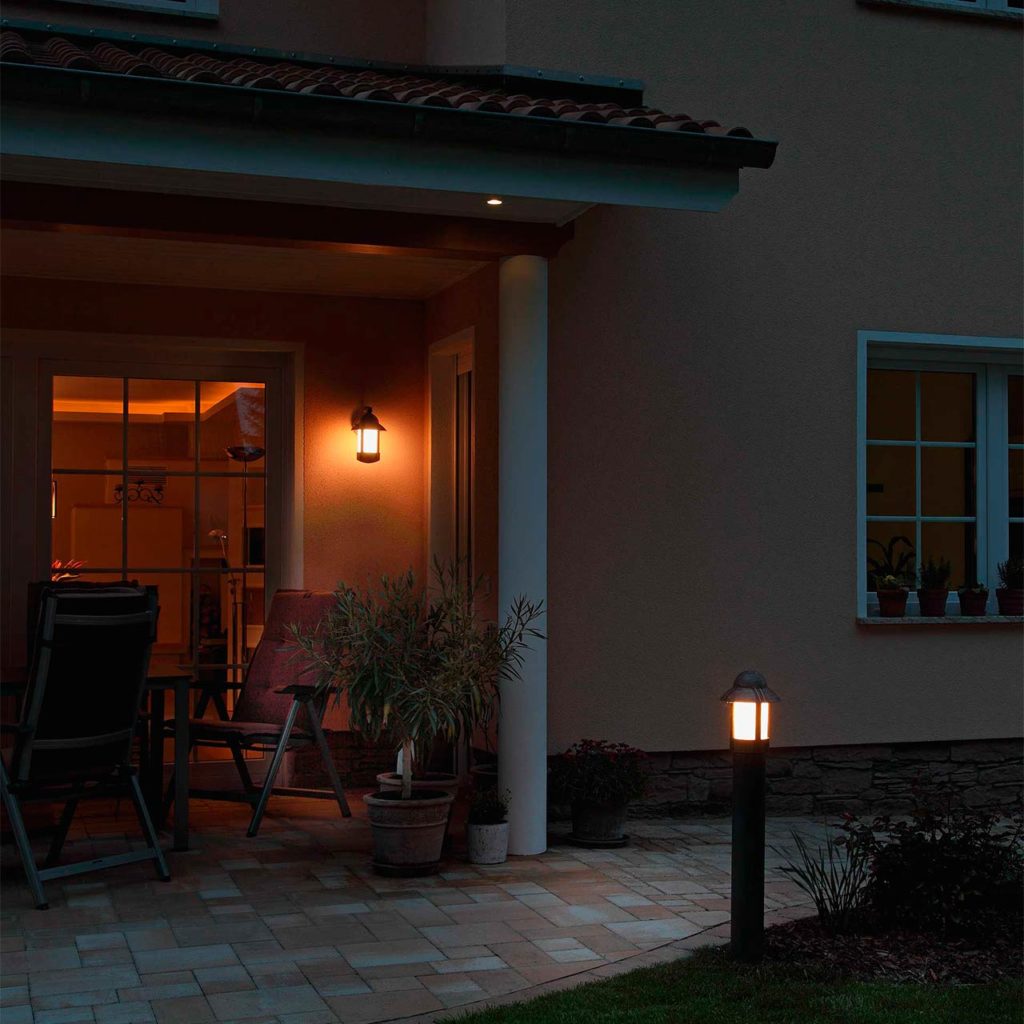 Eine Terrasse mit mediterranem Steinboden wird durch eine Terrassenleuchte und eine Sockelleuchte in Szene gesetzt.