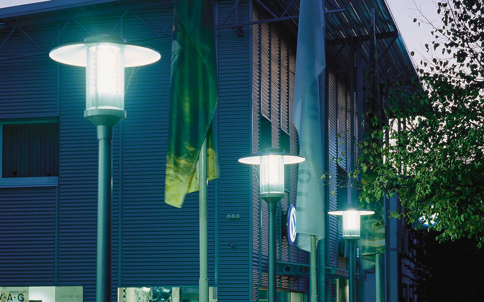 Several lanterns are lined up at a car dealership parking space.