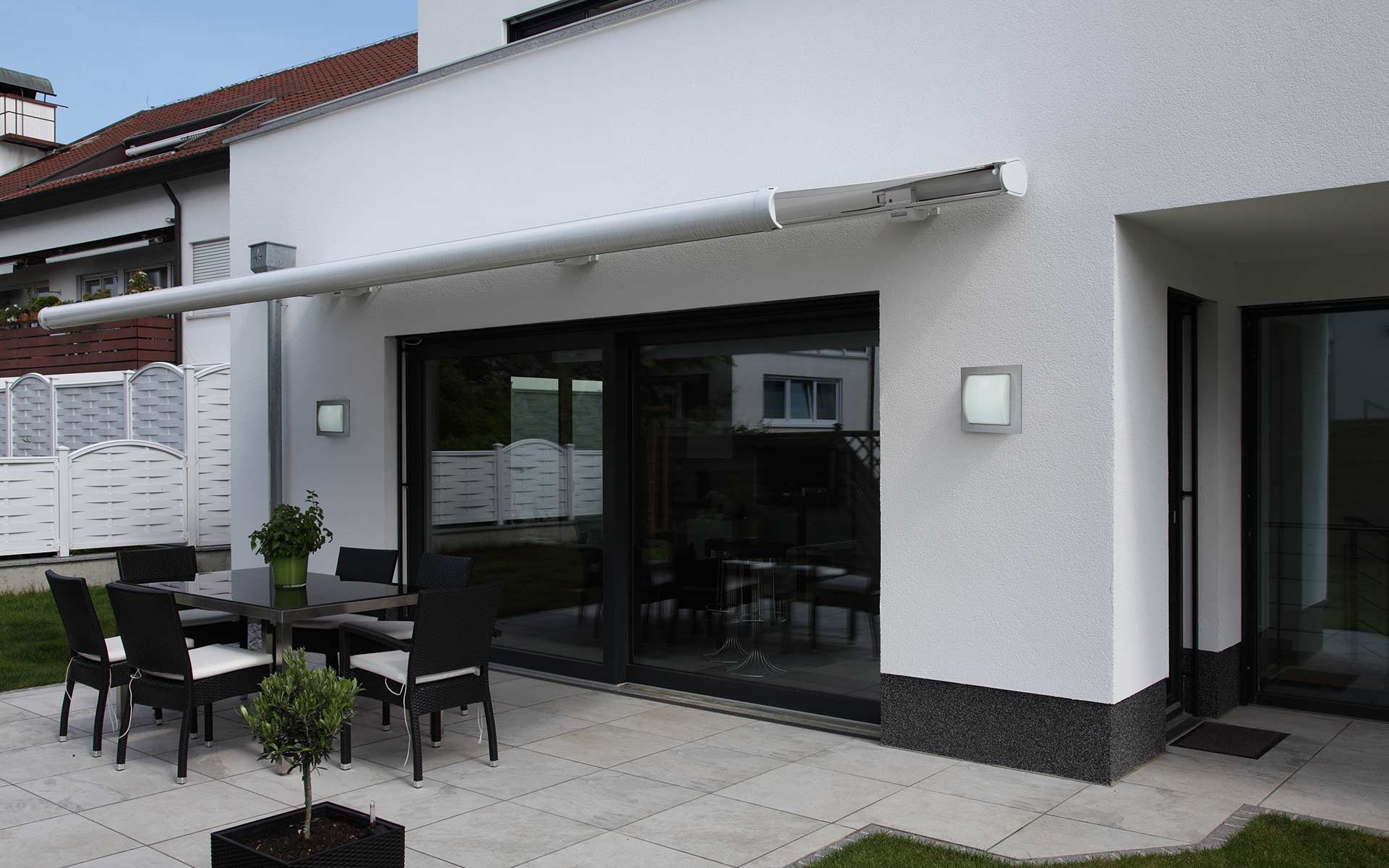 A modern terrace with an awning is visually completed by two Albert wall lights.